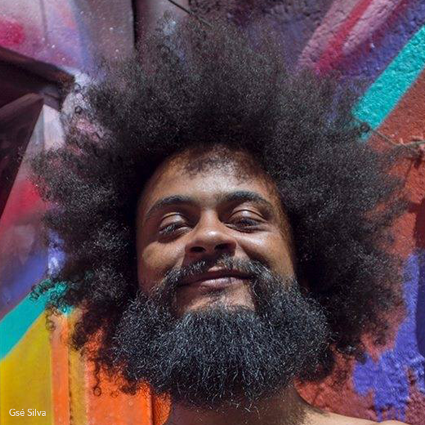 A man with a beard and afro is smiling for the camera