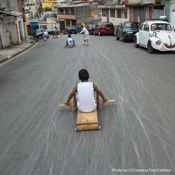 A boy is riding a wooden sled down a street