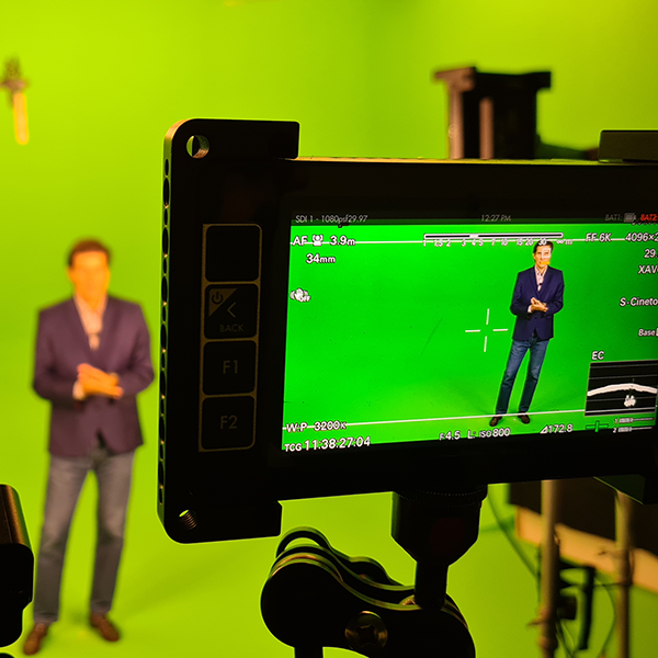 Live streaming from a set A man in a suit is standing in front of a green screen
