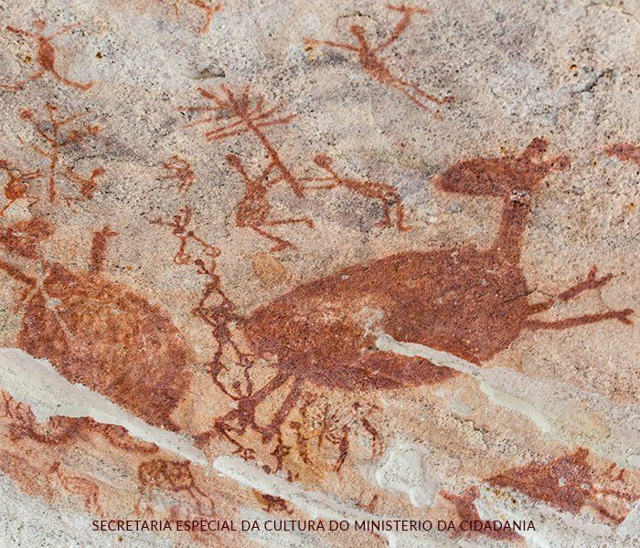 Une fresque qui présente des animaux et des hommes peints en rouge