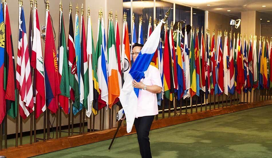 A man is holding a flag in front of a wall of flags.