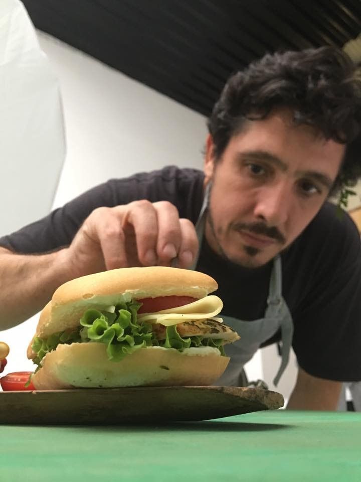 A man is putting a sandwich on a plate
