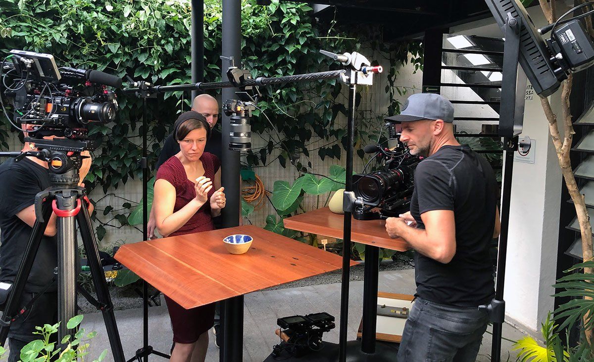 A man is taking a picture of a woman sitting at a table.