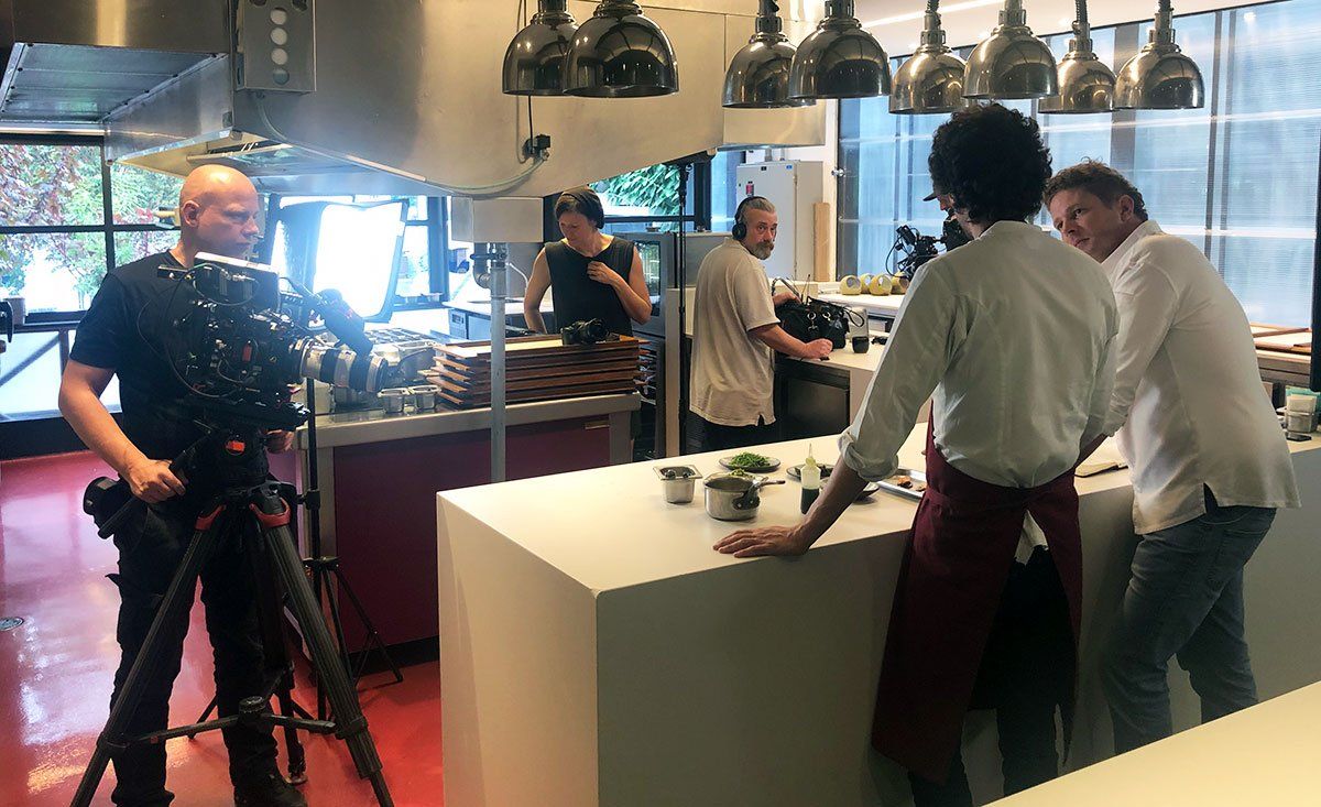 A man is standing in front of a camera in a kitchen.
