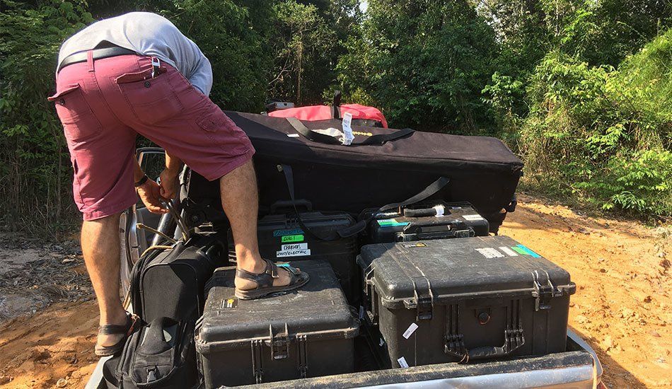 A man is loading luggage into the back of a truck.