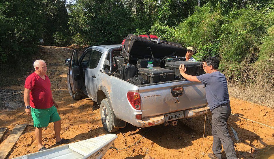 Two men are pushing a truck that is stuck in the mud.