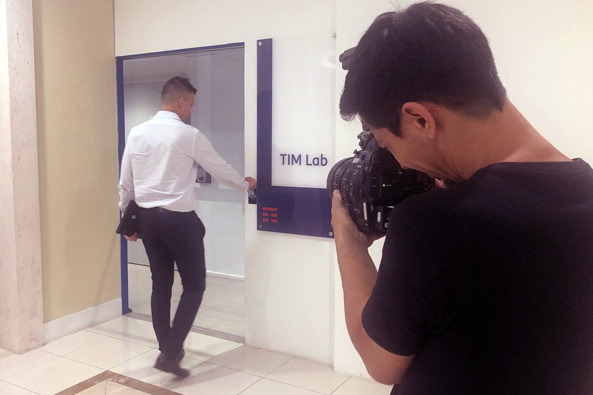 A man is taking a picture of another man using an atm machine.