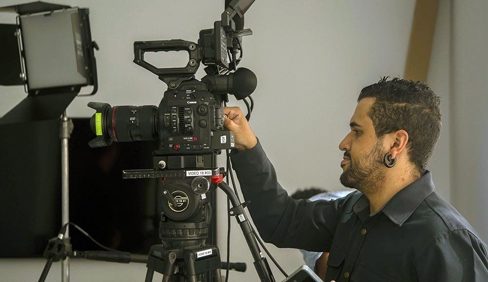 A man is adjusting a video camera on a tripod.