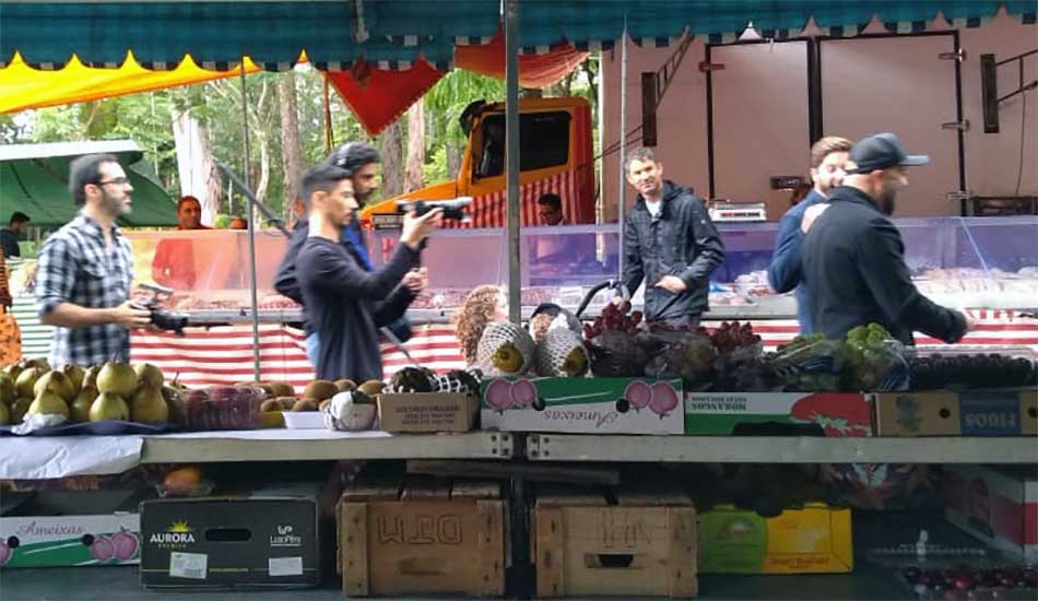 A group of people are standing around a fruit stand.