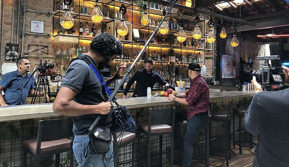 A man is standing in front of a bar holding a microphone.