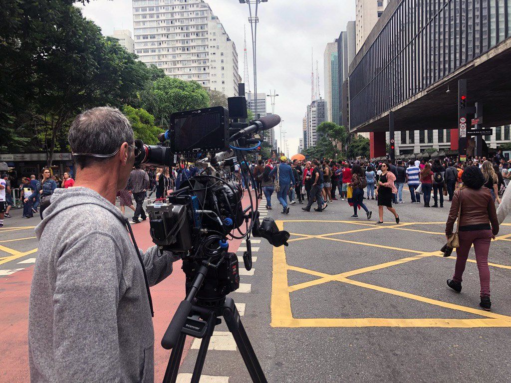 A man is holding a camera in front of a crowd of people