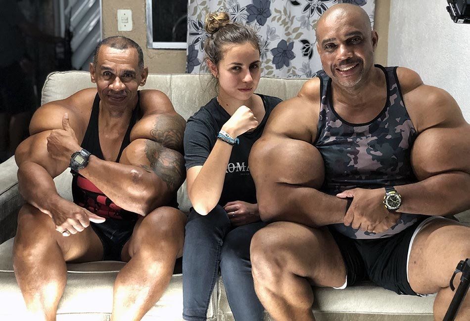Two men and a woman are posing for a picture while sitting on a couch.