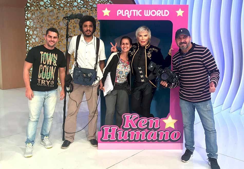 A group of people are posing for a picture in front of a plastic world sign.