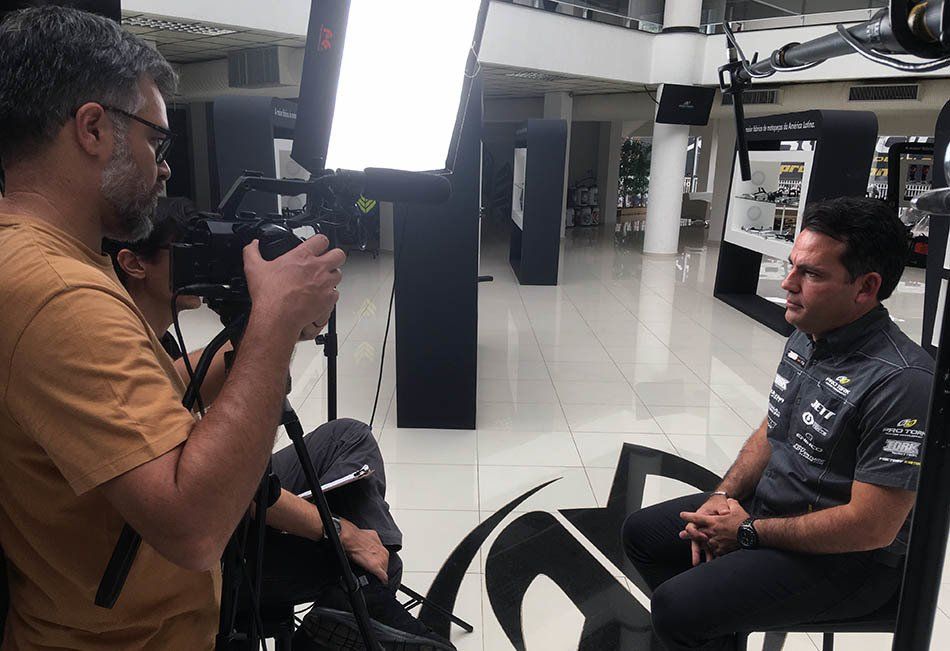 A man is sitting in front of a camera while another man takes a picture of him