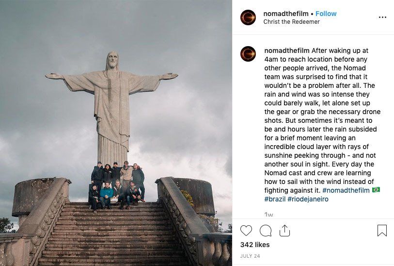 A group of people are posing for a picture in front of a statue of jesus.