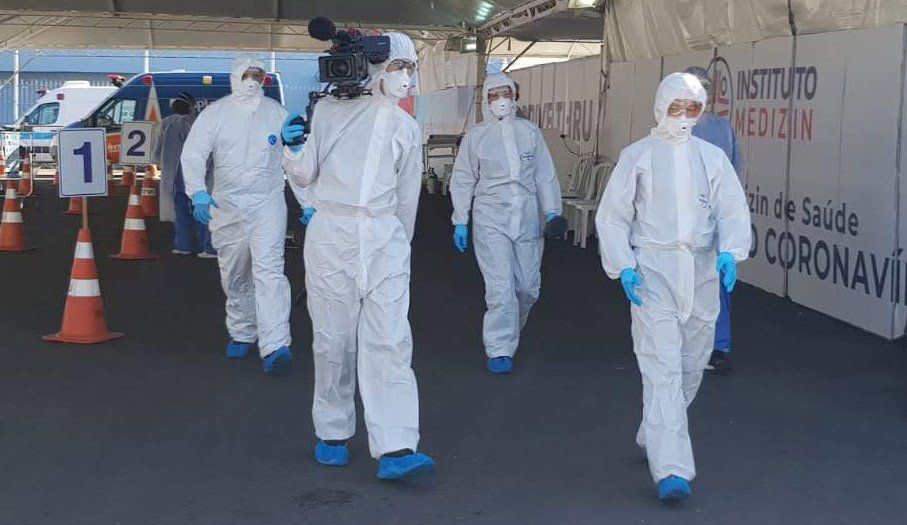 A group of people in protective suits are walking down a street.