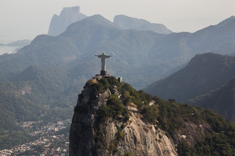 A statue of jesus is sitting on top of a mountain.