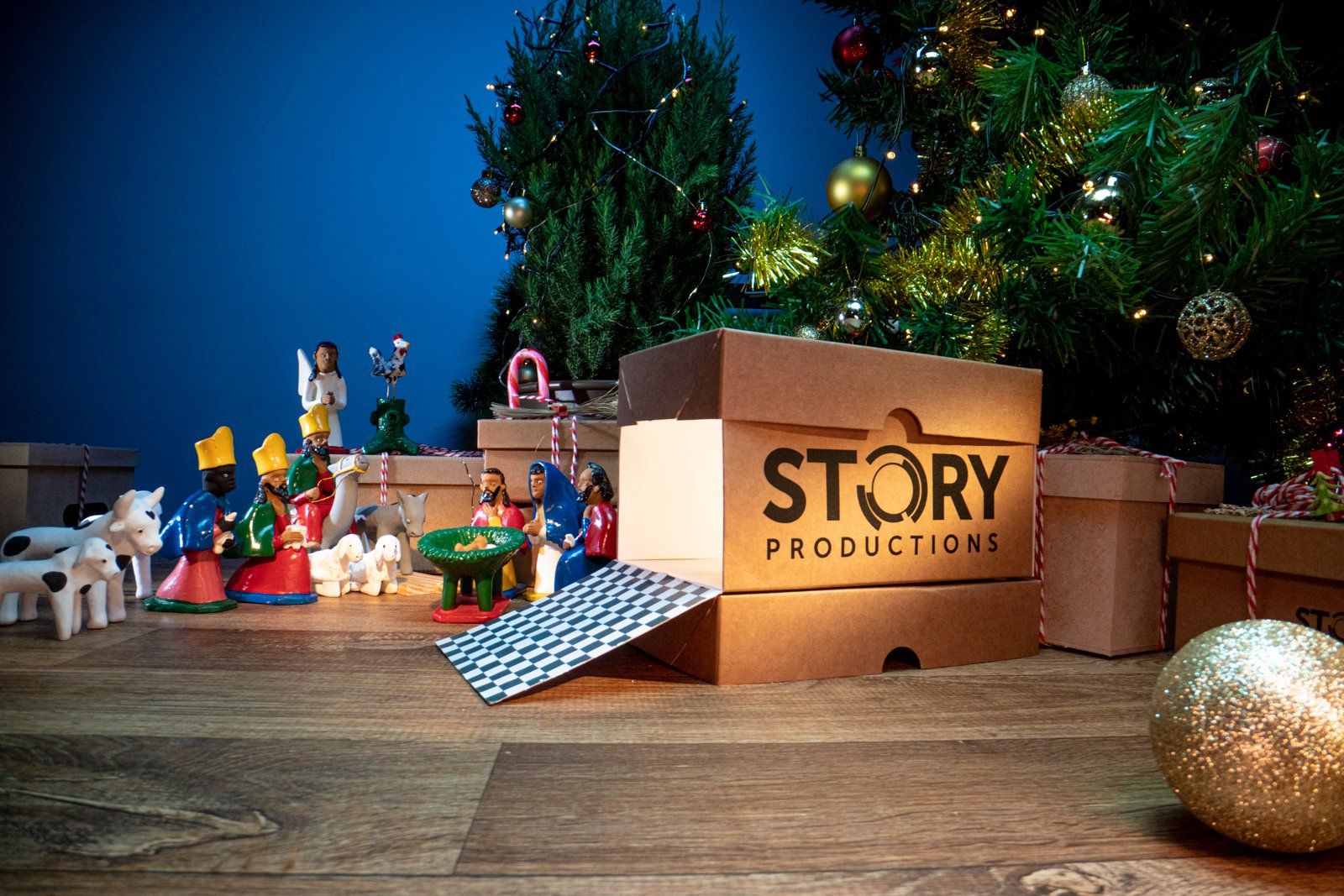 A story productions box is sitting on a wooden table next to a christmas tree.
