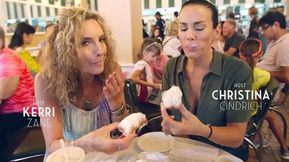 Two women are sitting at a table eating cotton candy.