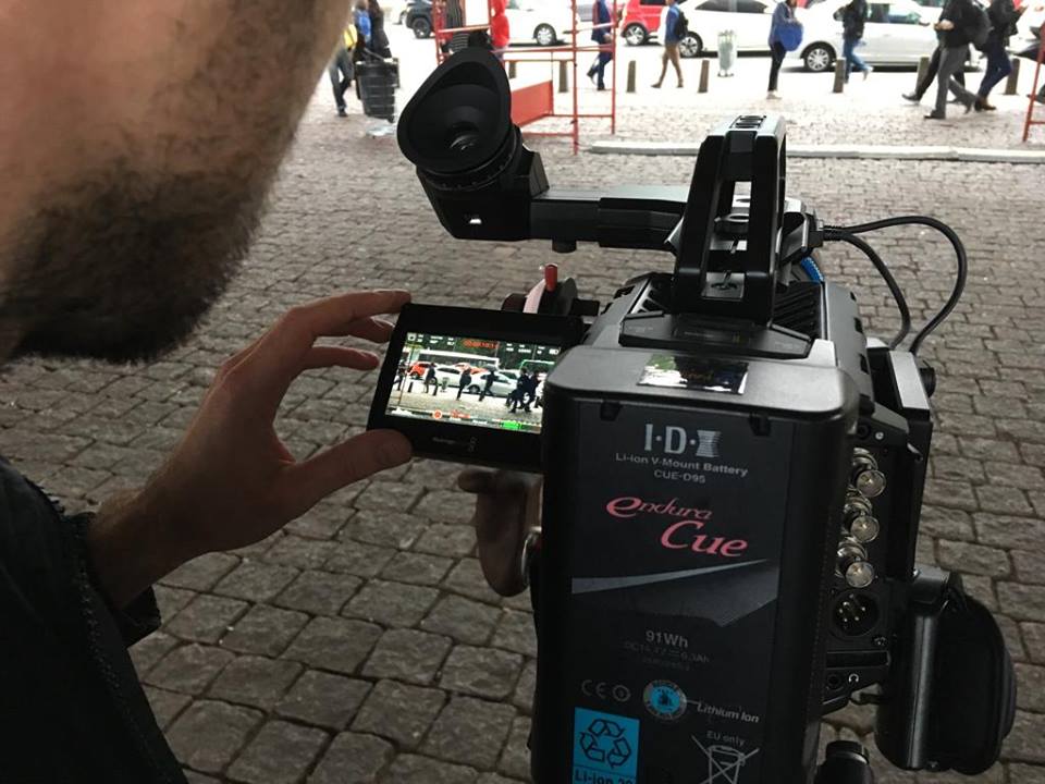 A man is holding a cell phone in front of a camera.