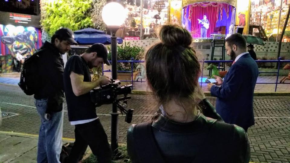 A group of people are standing around a woman holding a camera.