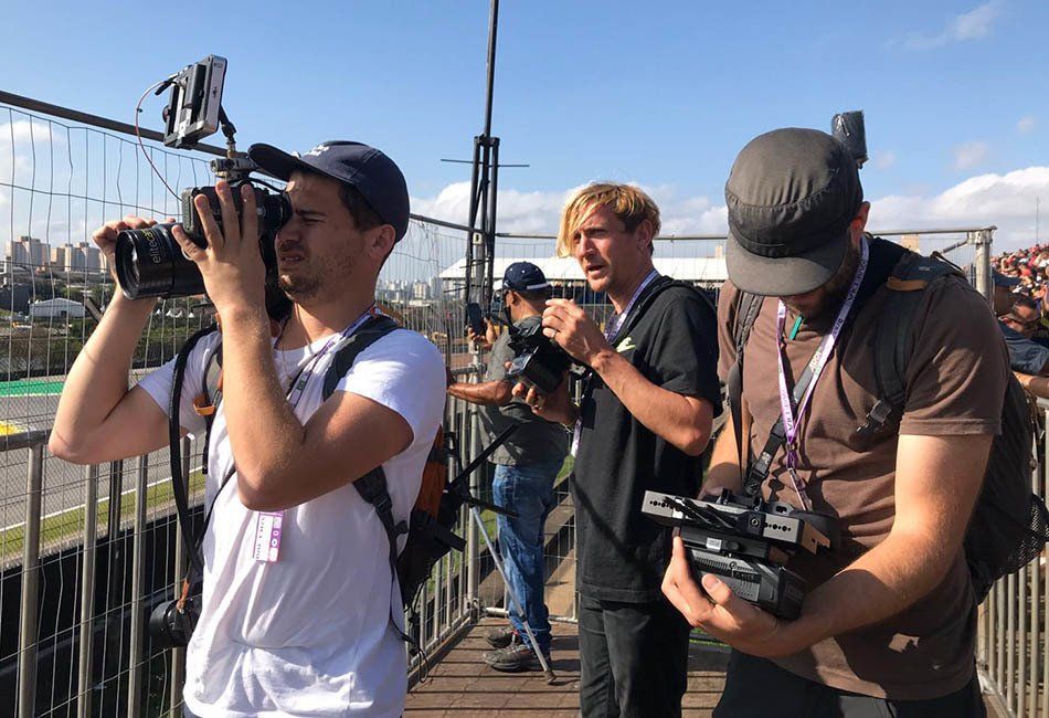 A group of men are standing on a bridge taking pictures with cameras.