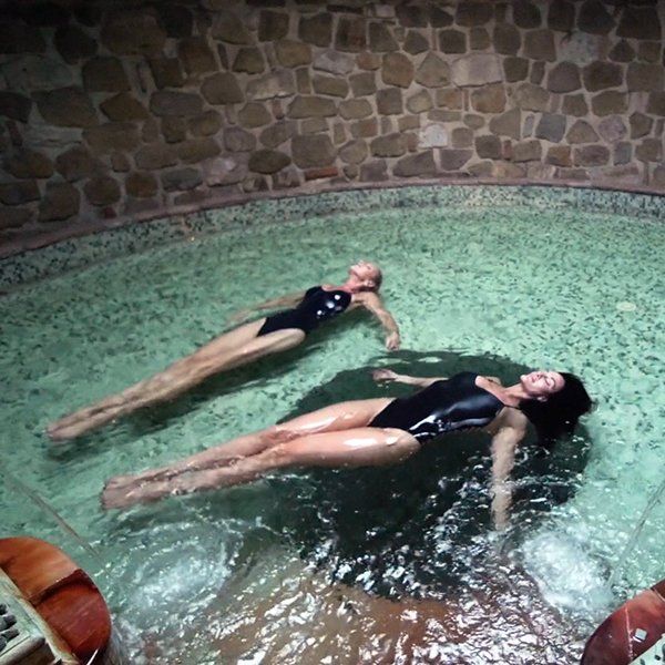 Two women in bathing suits are floating in a pool