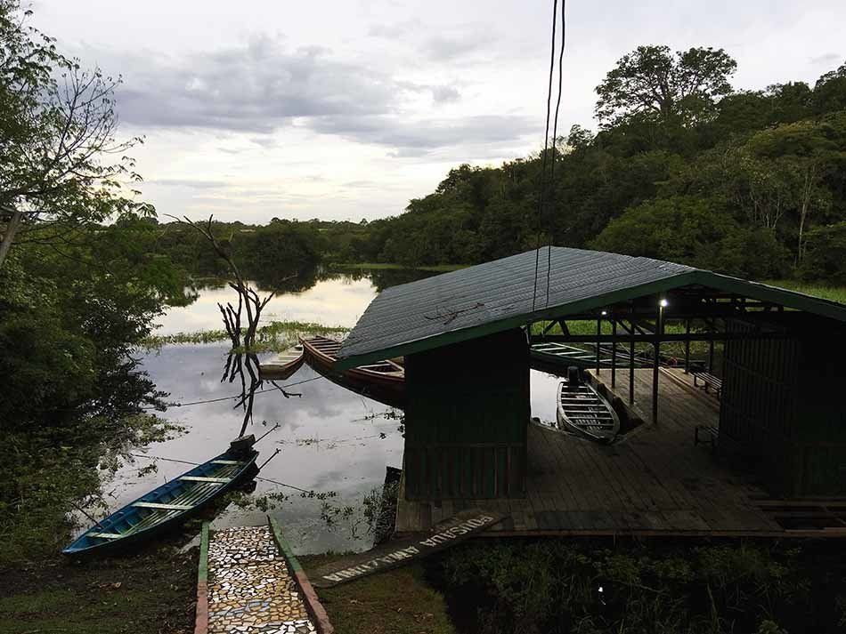 A boat is docked in front of a building on the shore of a lake.