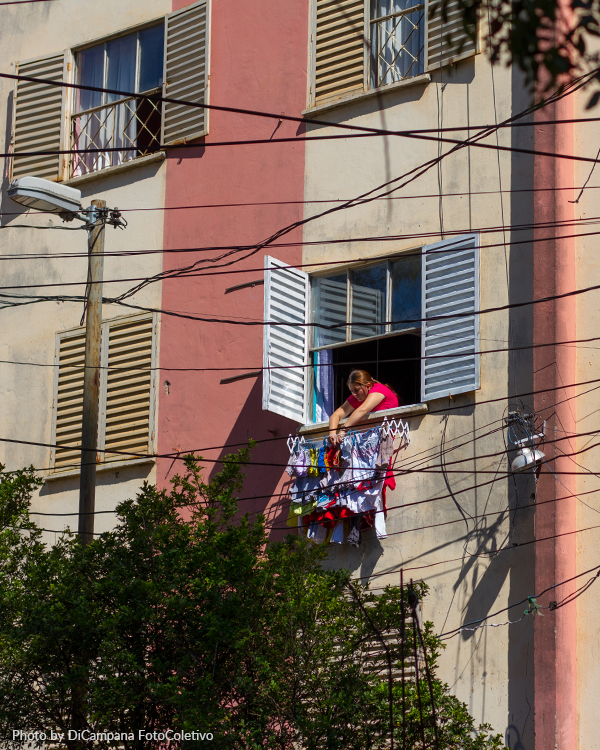 Photo by DiCampana Colectivo A woman sits on a balcony with clothes hanging out of it