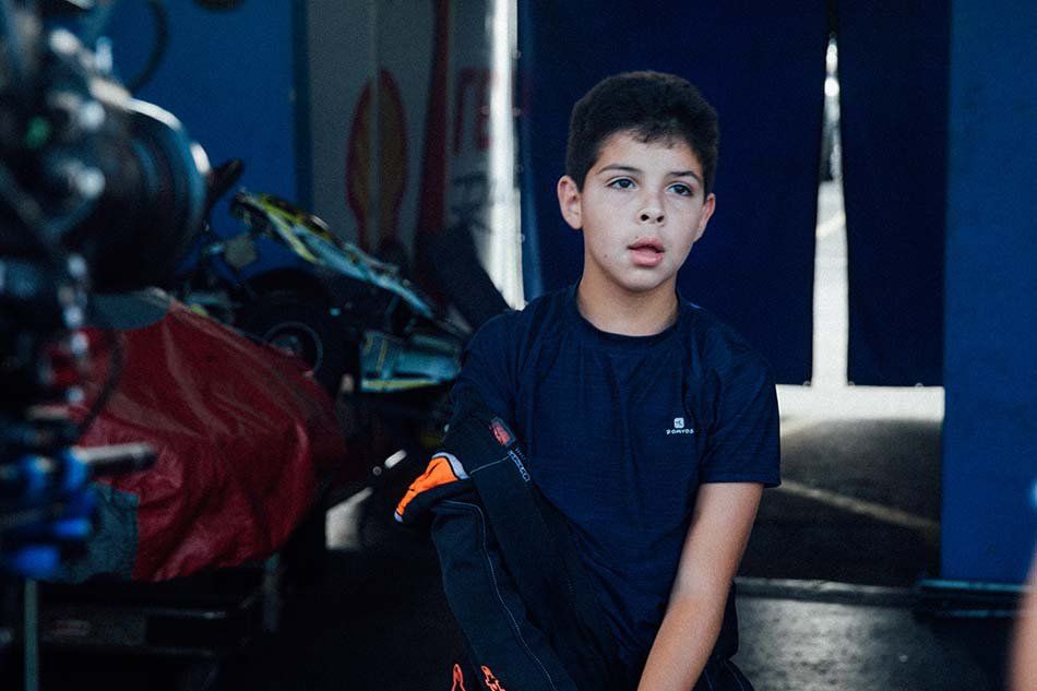 A young boy is sitting on the floor in a garage.