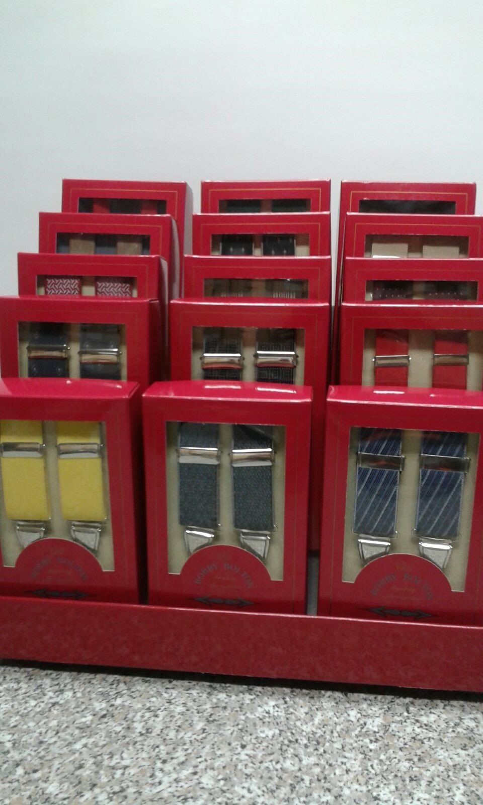 Red wooden display boxes with small framed panes arranged in rows on a speckled floor.