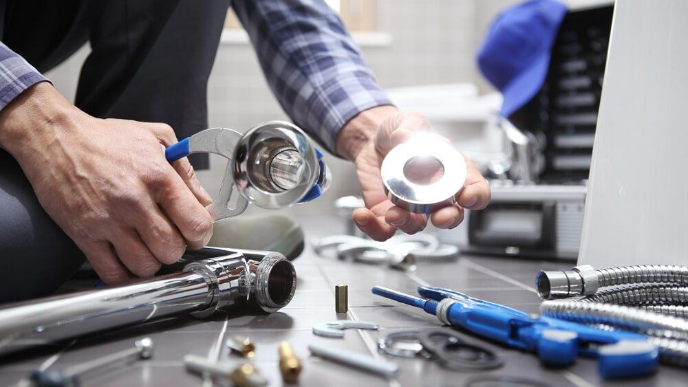 A plumber is working on a pipe with a wrench.