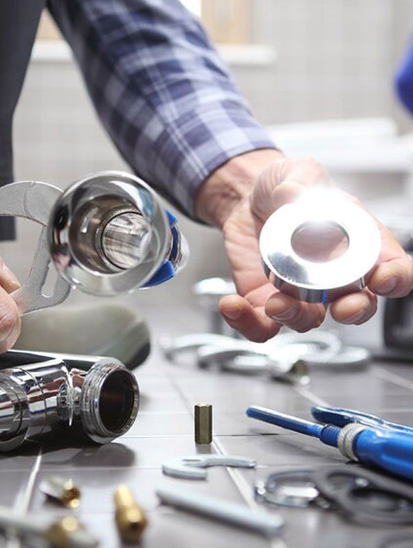 A man is holding a wrench and a piece of metal in his hands.