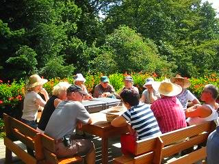 A group of people are sitting around a table in a park.