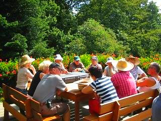 Een groep mensen zit rond een tafel in een park.