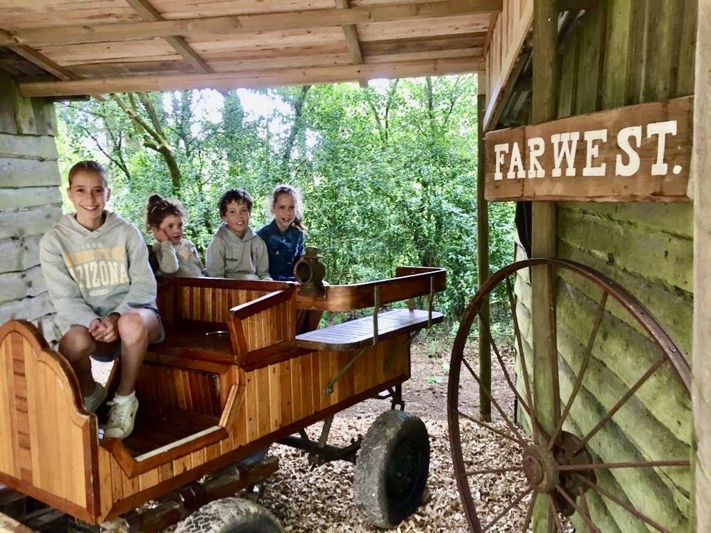 Een groep kinderen zit in een houten wagen.