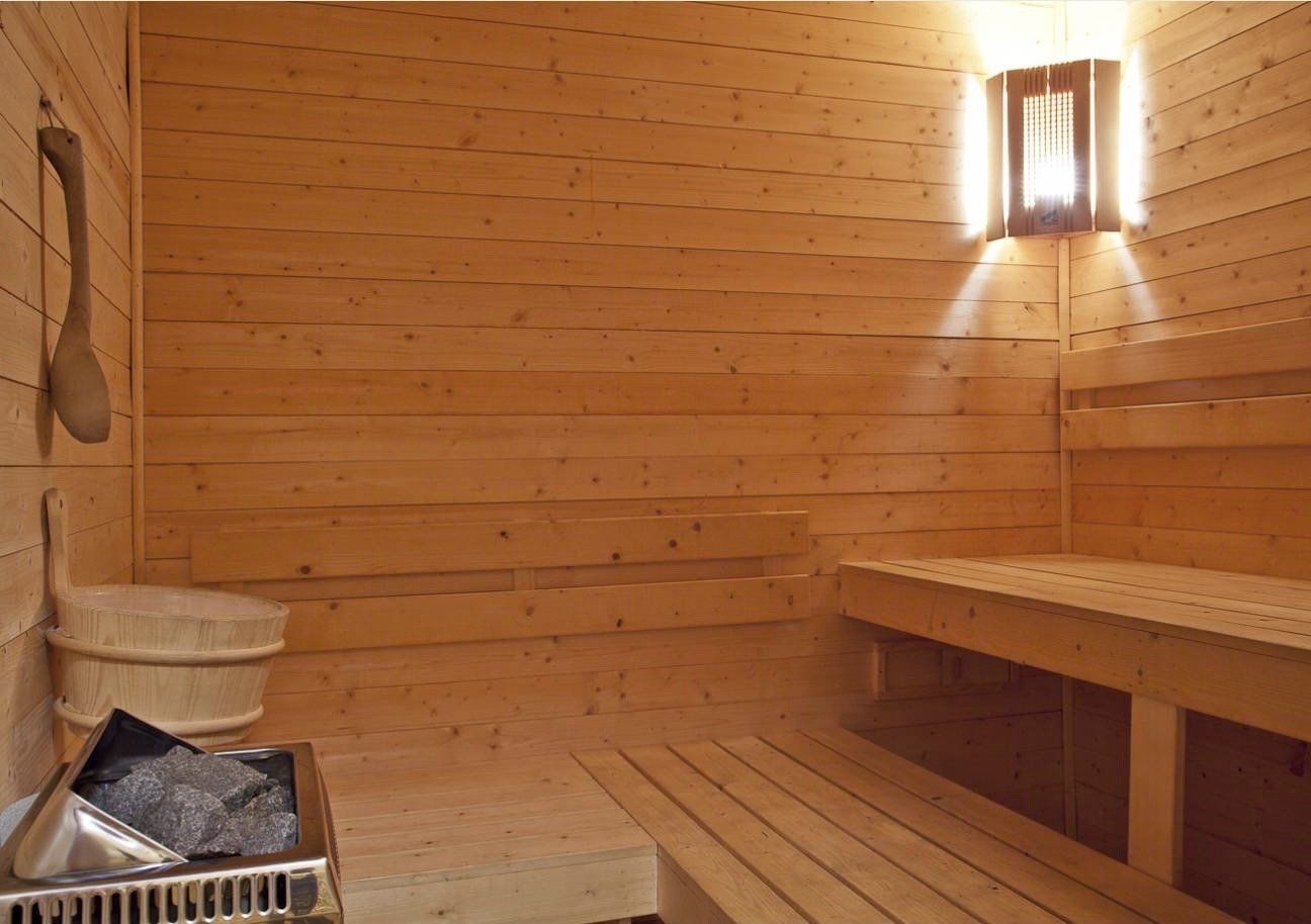 Een houten sauna met een emmer en een lamp aan de muur.