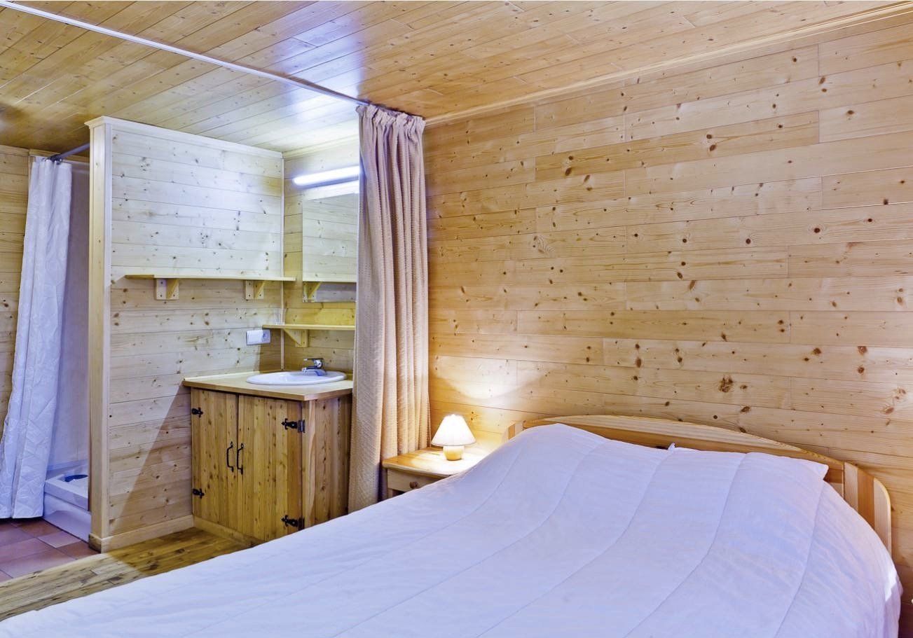 Een slaapkamer met een bed, nachtkastje, wastafel en spiegel.