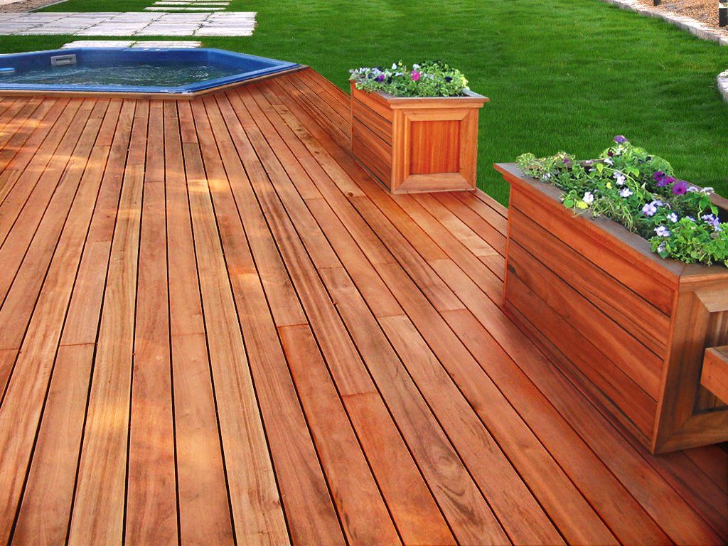 A wooden deck with planters and a hot tub in the background