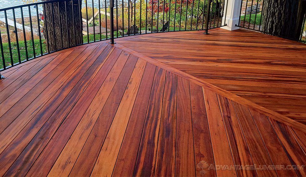 A wooden deck with a metal railing and a view of the water.