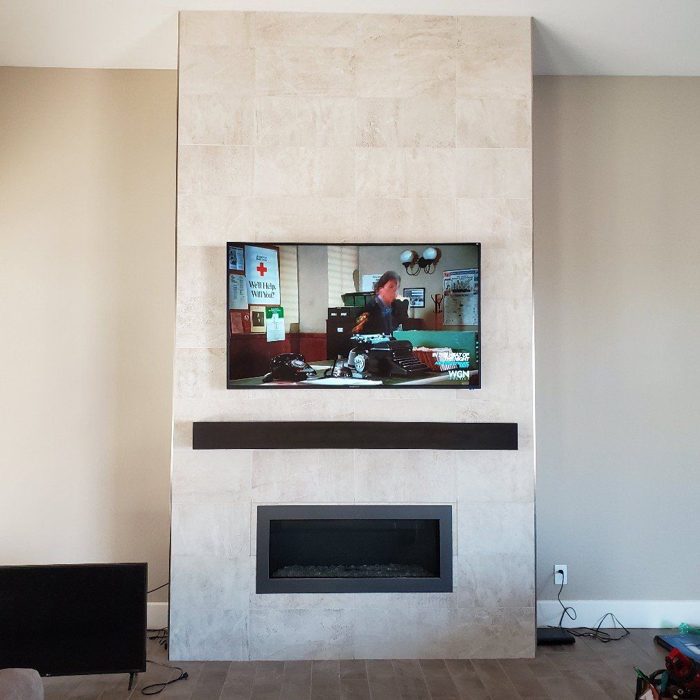 Fireplace with TV mounted above it on a light stone wall. A soundbar sits between them.