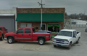 Two trucks are parked in front of a building with a green awning