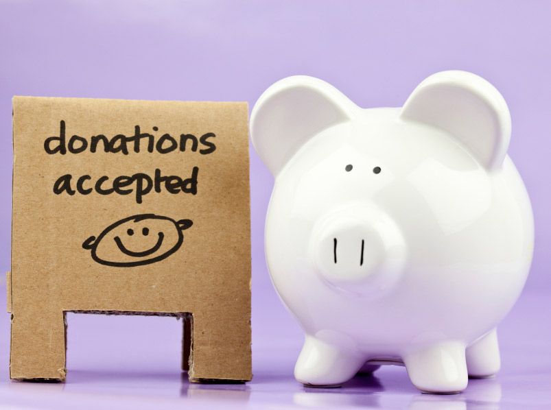 A piggy bank next to a cardboard box that says donations accepted