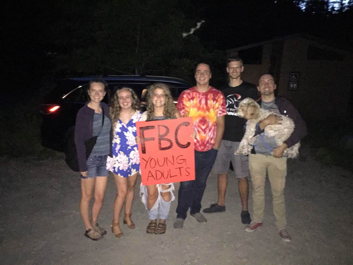 Group of young adults holding a sign that reads 