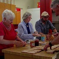 Four people making sandwiches at a table, likely for a charitable cause.