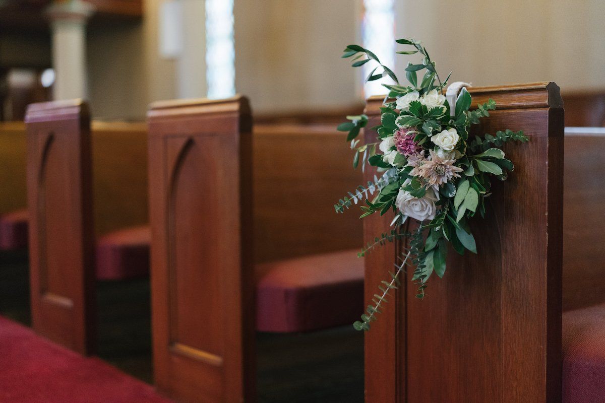 Church pew decorated with floral arrangement.