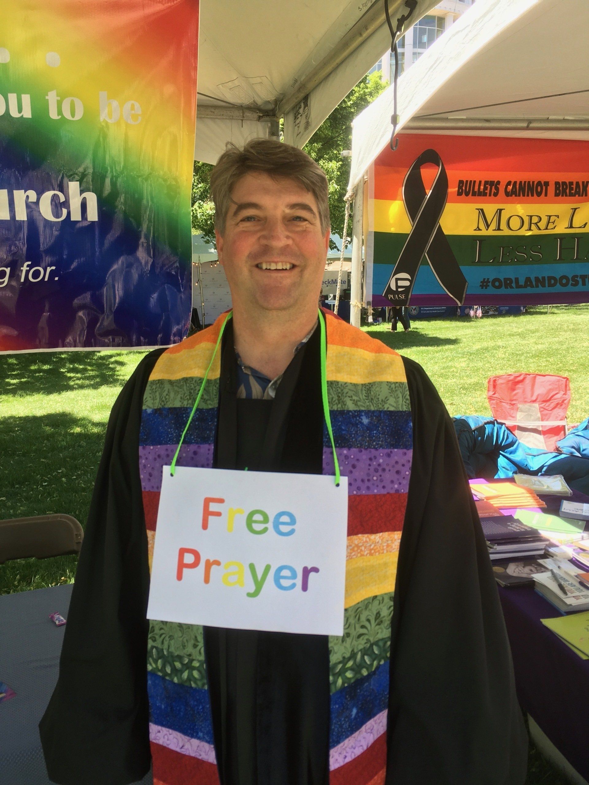 A man wearing a rainbow stole and a 