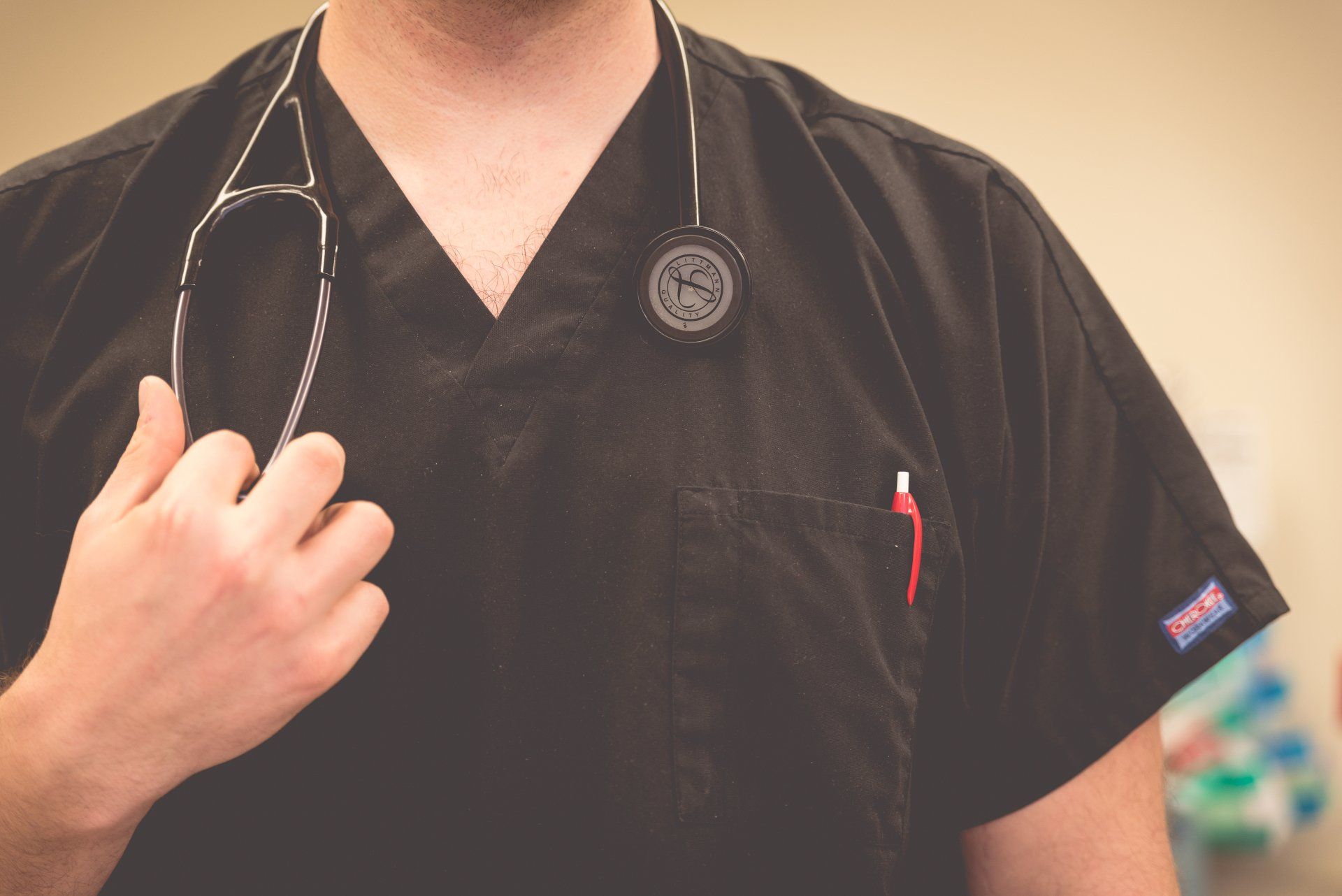 a doctor wearing a black scrub top with a stethoscope around his neck