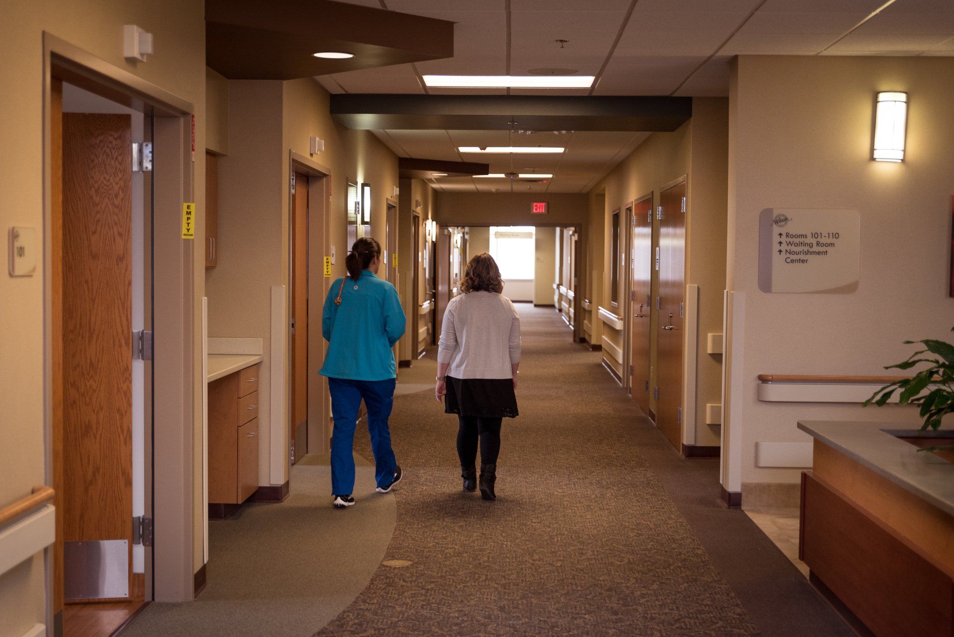 two women are walking down a hallway in a hospital