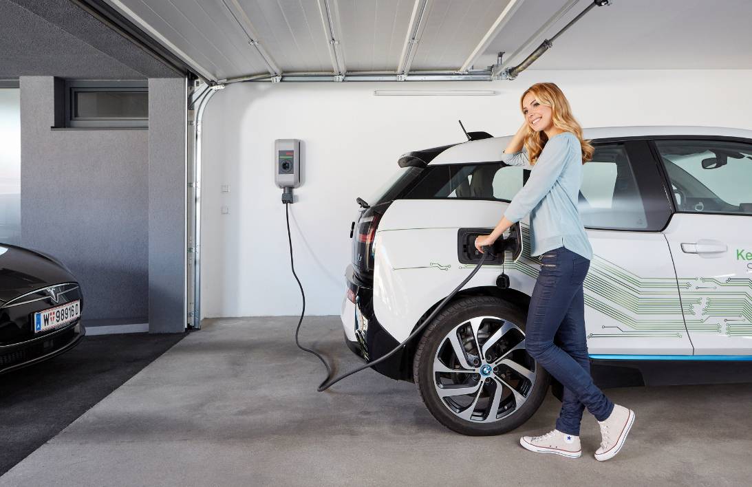 Woman charging electrical vehicle — Fort Myers, FL — Berkshire Bay Contractors Inc. Woman charging electrical vehicle — Fort Myers, FL — Berkshire Bay Contractors Inc.